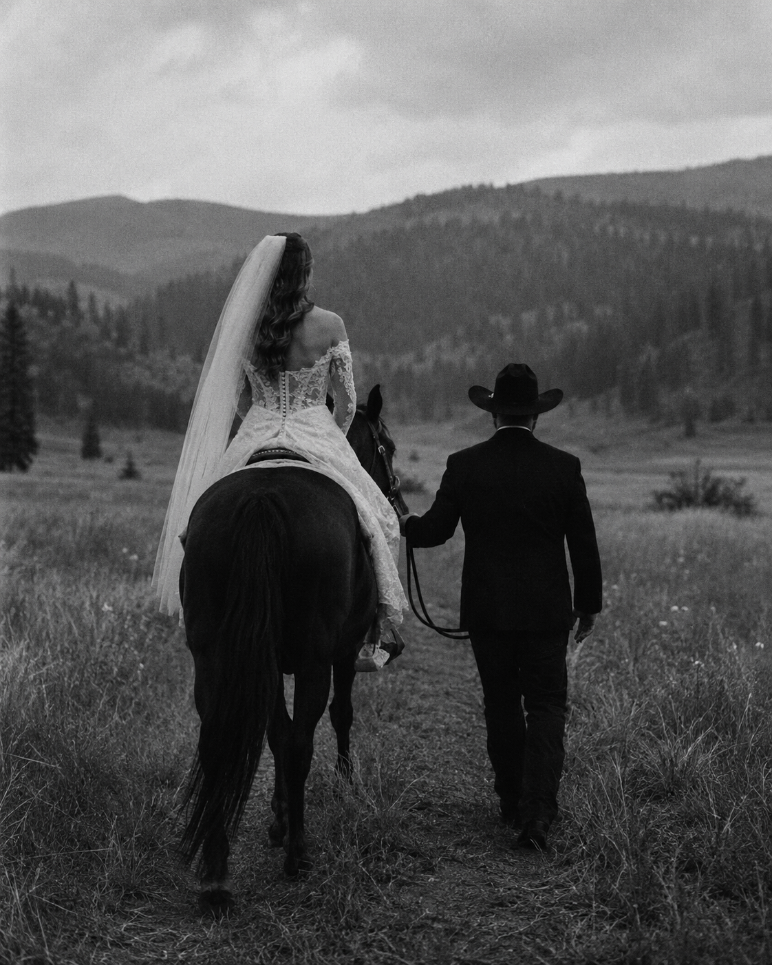 Bride on horseback led by the groom through a calm mountain field