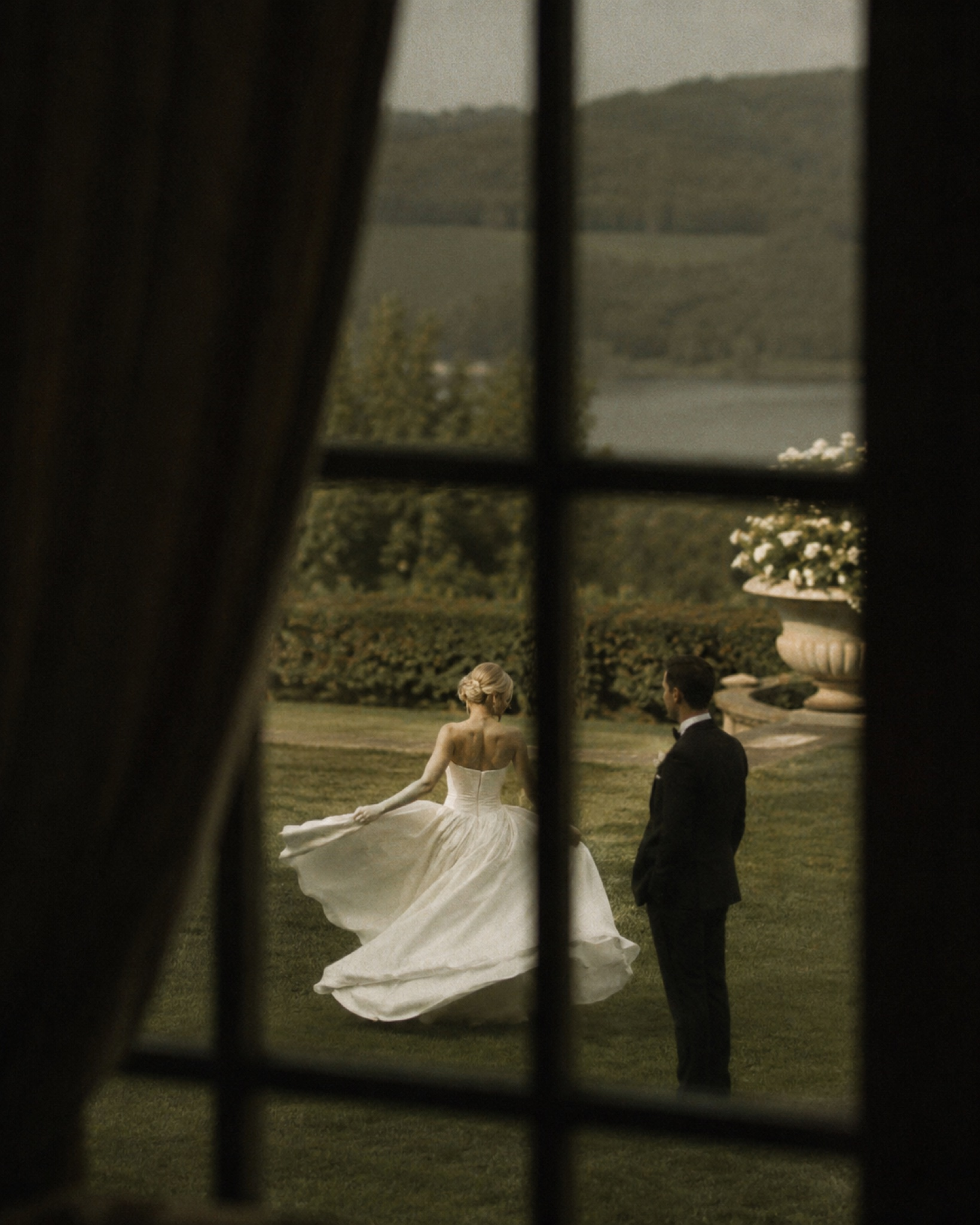 Bride and groom seen through a window, dancing together outdoors