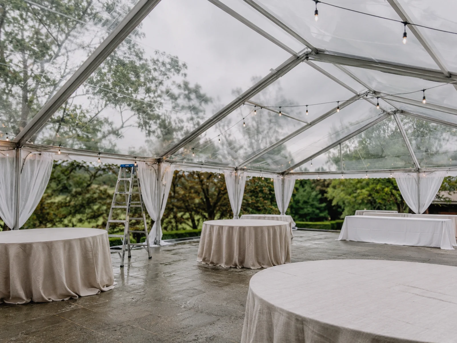 Clear-top tent set up as a weather backup with round tables and string lights