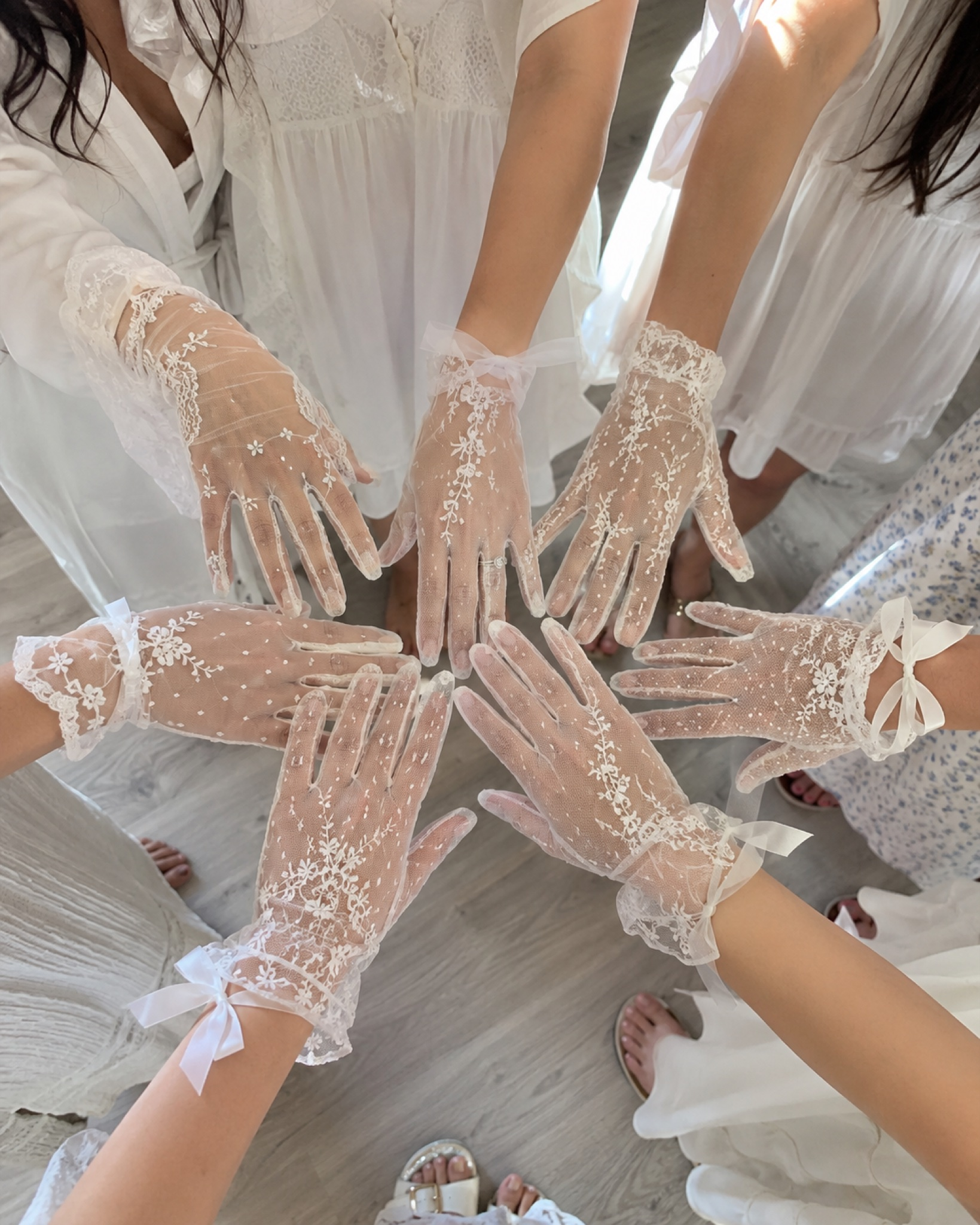 Bridesmaids in lace gloves touching hands together in a circle